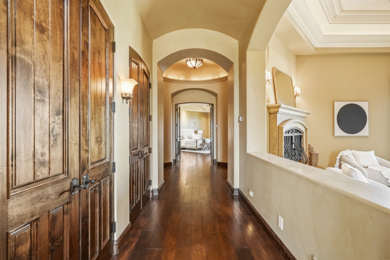 Traditional arched hallway with wood doors leading to the primary suite