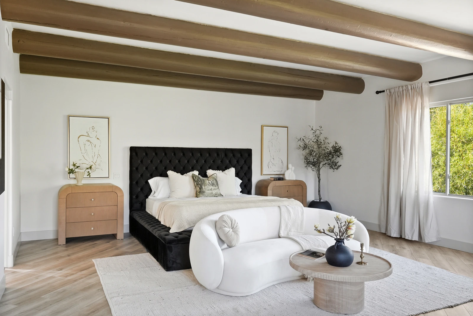 Primary bedroom with a black tufted headboard and rustic wood beams